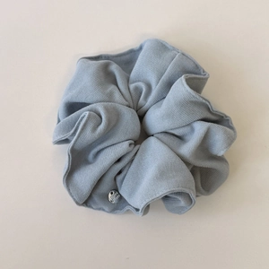 Close-up of blue-gray knitted hair scrunchie with vertical texture and silver metal tag