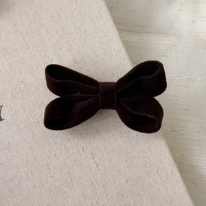 Close-up of a vintage dark brown velvet bow hair clip showing soft fabric texture