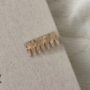 Detail of acetate hair comb with faux pearl texture and sparkling rhinestones