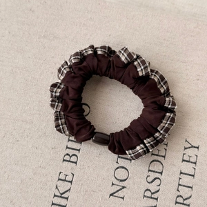 Detailed close-up of brown plaid lace scrunchie with layered ruffles and center bead