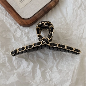 Close-up of black leather and gold metal chain woven details on large hair claw clip