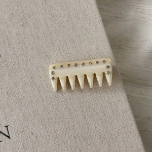Close-up of beige acetate hair comb with sparkling rhinestones on textured surface