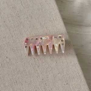 Detail of pink marbled acetate hair comb with sparkling rhinestones on fabric background