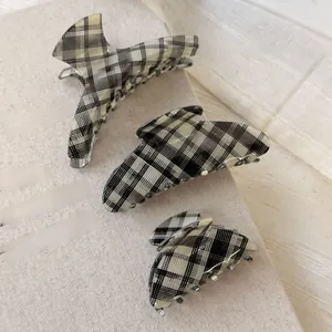 Three-piece set of black and white checkered acetate hair claws on a textured book