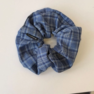 Détail d'un chouchou en tissu écossais bleu avec motif à carreaux et plis souples