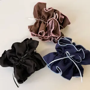 Detailed view of layered fabric hair ties in brown, black and navy with ribbon bows