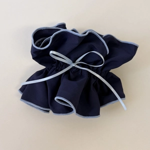 Detailed view of dark blue ruffle hair tie with light blue ribbon bow and stitching