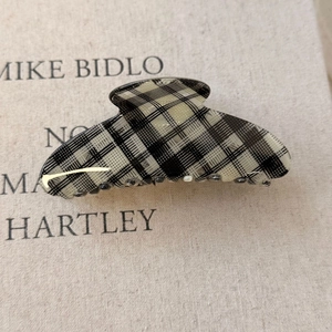 Detail view of checkerboard hair claw clip made of acetate on a minimalist beige book