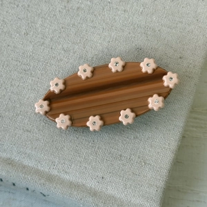 Détail d'une pince à cheveux en acétate ambré avec fleurs roses et cristaux