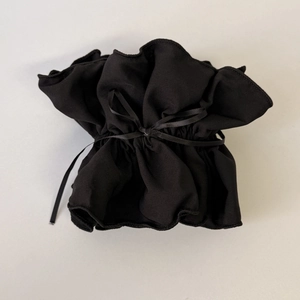 Close-up of black fabric drawstring gift bag with pleated edge and satin ribbon tie