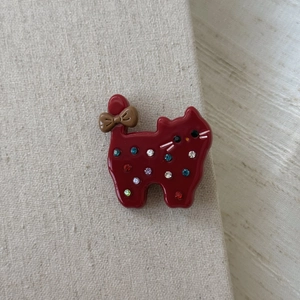 Close-up of deep red acetate cat hair clip with colorful rhinestones and brown bow