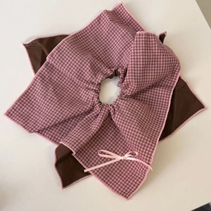 Close-up of pink gingham bow hair tie with layered fabric and elastic gathered center