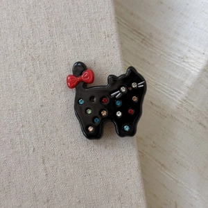 Elegant black acetate cat hair clip with red bow and colorful rhinestones on fabric