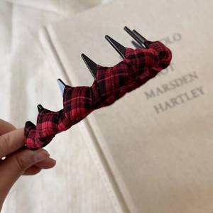 Detail showing the red and black plaid fabric texture and dark punk spikes on the headband