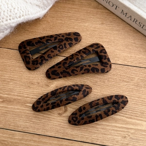 Leopard print BB hair clips set in triangle and oval shapes on a rustic wood background