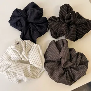 Set of four striped fabric scrunchies in black, brown, and white with handmade labels