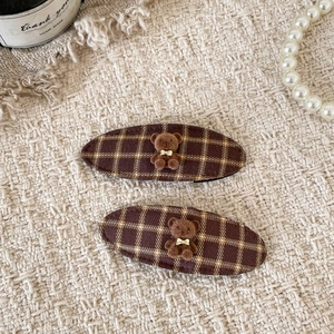 Close-up of brown plaid hair clips with cute plush bears and golden bowties