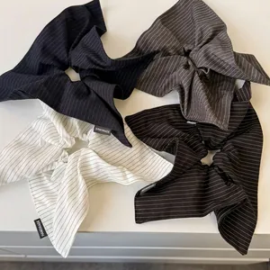 Striped bow scrunchies set in four colors with handmade label on a clean surface