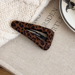 Detail of leopard print fabric texture on a triangular metal BB hair clip for women