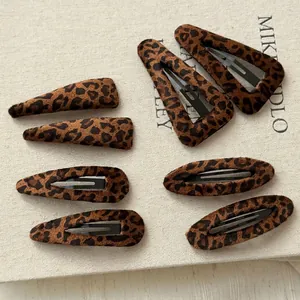 Set of 8 vintage leopard print hair clips in various shapes on beige textured canvas