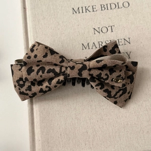 Detail of leopard print bow hair clip with canvas texture and gold metal accent