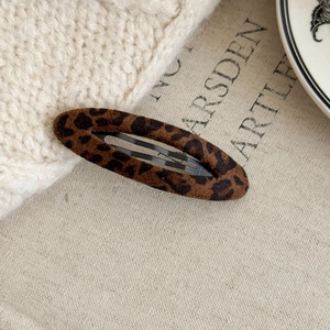 Macro shot of leopard print fabric texture and sturdy black metal clip of the hair accessory