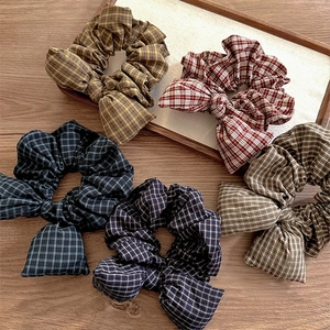 Set of five colorful grid pattern bow scrunchies displayed on a rustic wooden tray