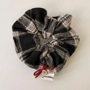 Detail von kariertem Scrunchie mit roter Schleife, Holzknopf und Happiness Etikett