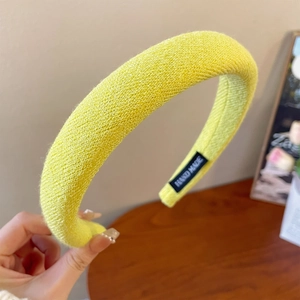 Detail of a bright yellow padded headband with hand made tag and knit texture