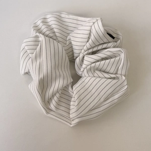 Close-up of white scrunchie with fine black stripes and soft fabric texture detail