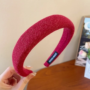 Detailed close-up of red chunky knit headband featuring a Hand Made woven label inside