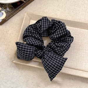 Detailed view of black and white grid bow scrunchie on a woven tray setting