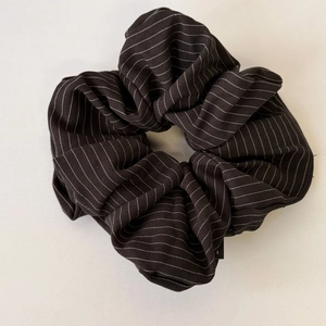 Macro detail of high-quality large black fabric scrunchie with white striped pattern