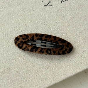 Close-up of leopard print plush hair clip with soft faux fur texture and black metal base