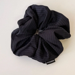 Close-up of handmade black and white striped scrunchie with vertical patterns and woven label