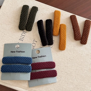 Set of twill fabric hair clips in assorted vintage colors on a cream textured background