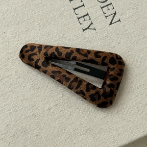 Macro shot of leopard print fabric texture and black metal finish on the BB hair clip