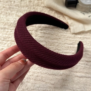 Detail view of burgundy wide headband showing textured ribbed knit fabric and non-slip lining