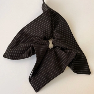 Detail of striped fabric scrunchie with large bow and handmade label on white background