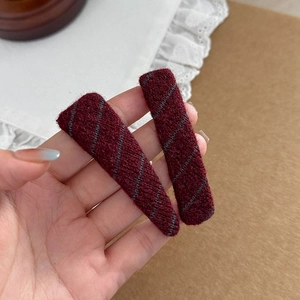 Detailed macro view of burgundy knit hair clips with grey diagonal striped texture