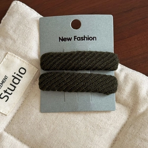 Close-up of olive green twill fabric BB hair clips on display card with knit texture
