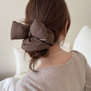 Gros plan sur un élastique à nœud marron bouffant montrant la texture mate et les détails 3D