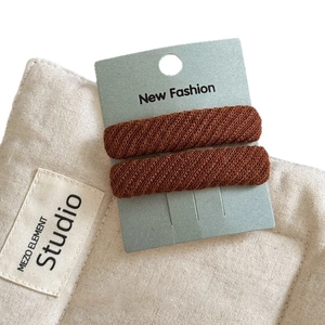 Pair of brown twill fabric BB hair clips with knitted texture on fashion display card