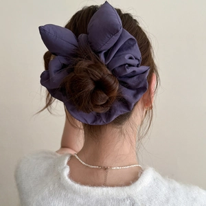 Vue détaillée d'un grand chouchou nœud bleu marine porté sur un chignon élégant
