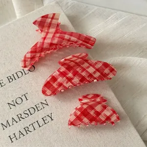 Set of three vintage red checkered hair claws in various sizes on a rustic book