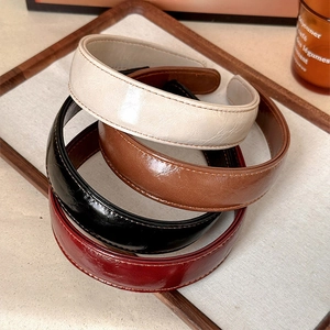 Vintage wide leather headbands in beige, brown, black, and burgundy on a tray
