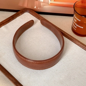 Close-up of deep brown leather headband with fine stitching and vintage texture detail