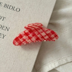Detailed close-up of a vintage red checkered hair claw clip on a rustic linen background