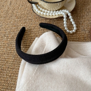 Detail view of black twill fabric wide headband with textured weave on white sweater