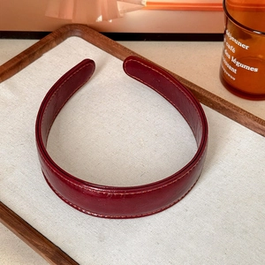 Detail of burgundy vintage faux leather wide headband with fine stitching on fabric tray